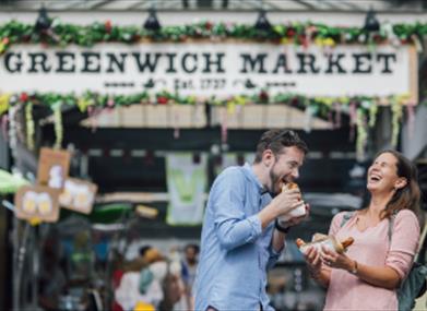 A couple enjoy food at Greenwich Market.