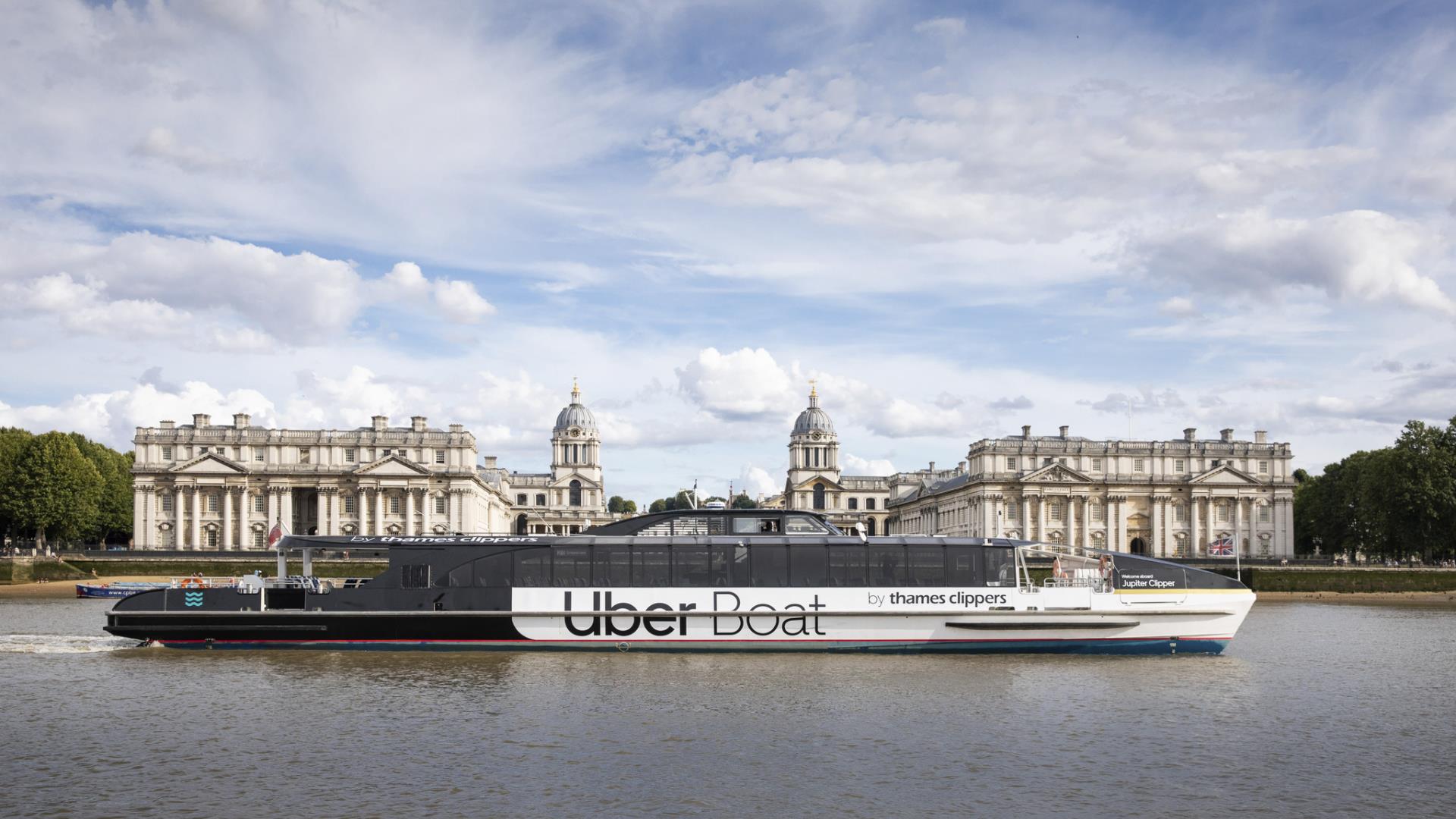 The Uber Boat by Thames Clippers as it passes the Old Royal Naval College on the river Thames.