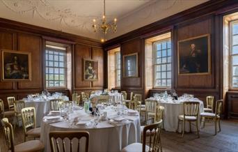 White banqueting rounds on wooden floor and pictured walls at the Admiral's House, Old Royal Naval College