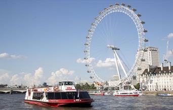 Red and white City Cruises boat on the River Thames passing the London Eye