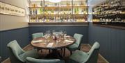 Inside the Office at Davys Wine Vaults, a small room with  a six seater round table and shelves filled with wine.