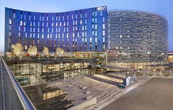 Main view of the Aloft London Excel exterior with deep blue and purple shades during evening time