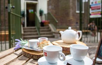A teapot and teacups laid out on a table outside Severndroog Castle in the sunshine.