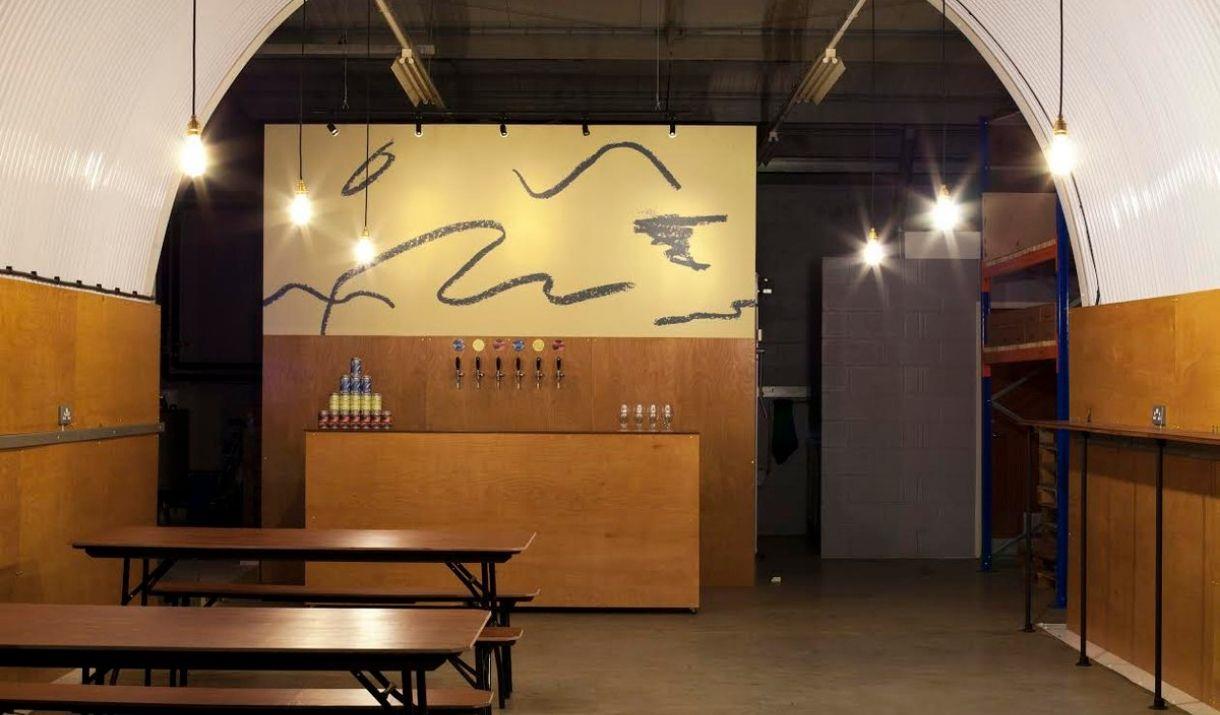 Inside of Villages Taproom Brewery with bar station in the background, benches to the left side and standing table on the right side Inside of Villages Taproom Brewery with bar station in the background, benches to the left side and standing table on the right side