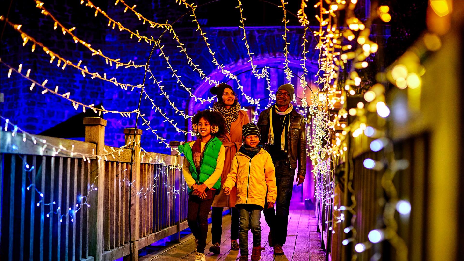 A family walk through a tunnel of fairy lights at Enchanted Eltham Palace in Greenwich