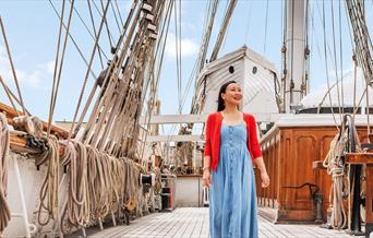 A lady stands on the upper deck of Cutty Sark in Greenwich, London.