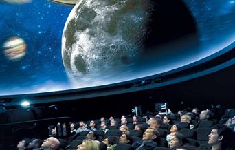 People sit in awe under the stars projected on the ceiling of the Peter Harrison Planetarium.