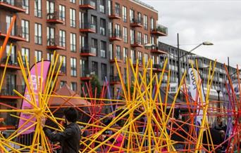 Everyone is invited to play their part in creating a huge structure from wooden rainbow coloured sticks.