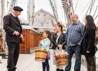 A family speak to the captain of the Cutty Sark in Greenwich.