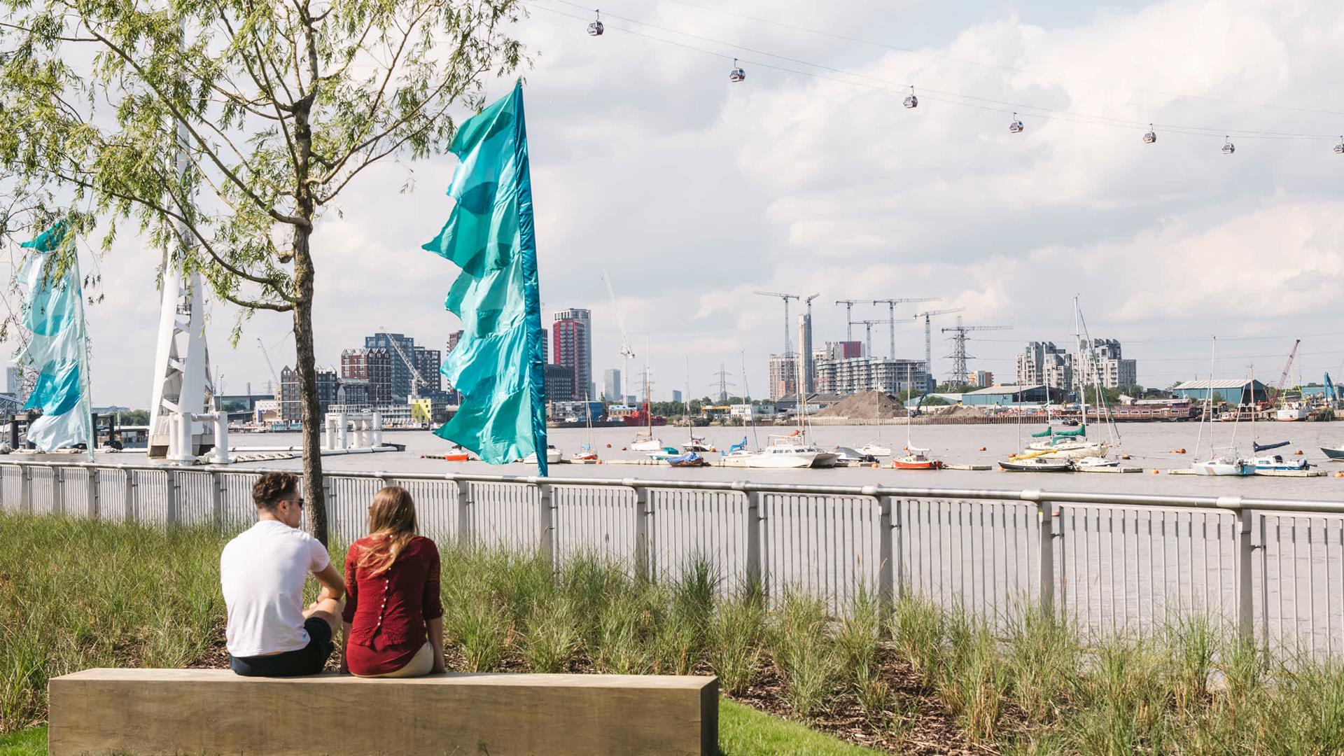 Two people sit beside the river in Greenwich