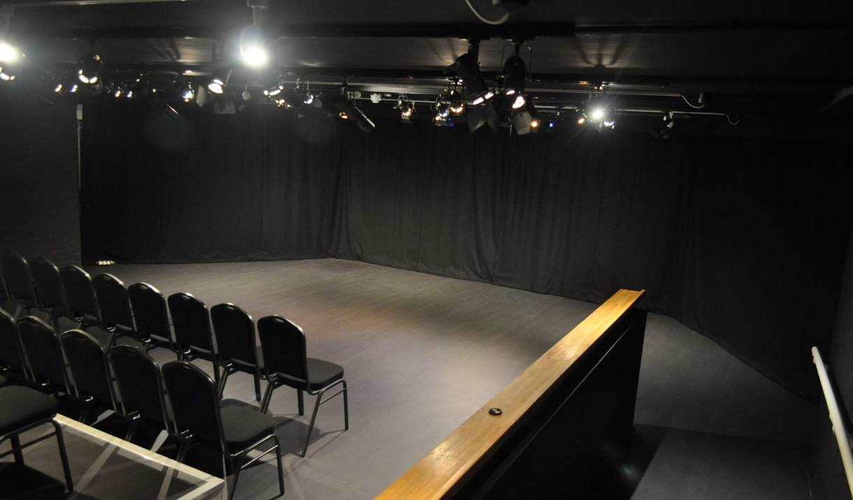 A blacked out studio room with a seating area and performing area. A blacked out studio room with a seating area and performing area.