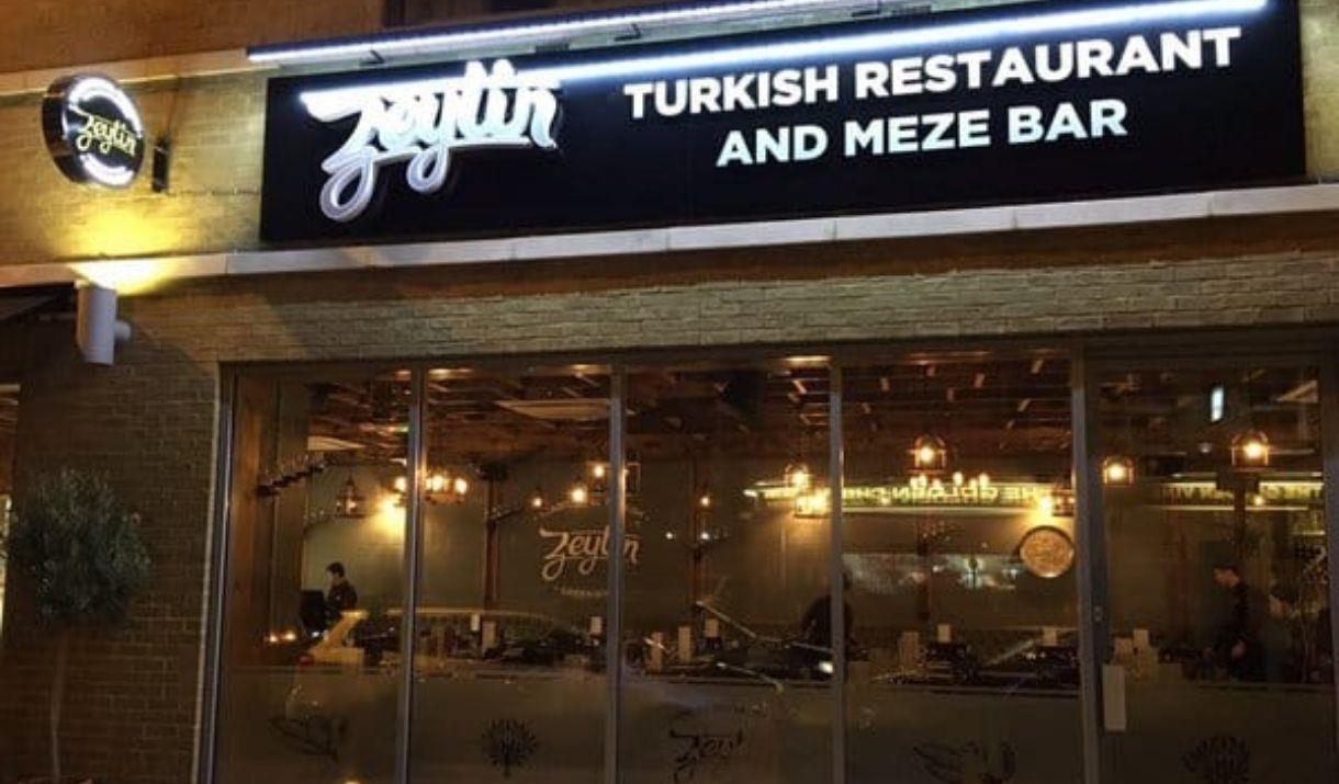 Exterior image of Zeytin Restaurant with glass entrance and warm lighting. Exterior image of Zeytin Restaurant with glass entrance and warm lighting.